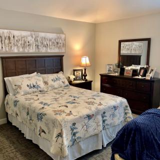 Cozy bedroom with a neatly made bed and wooden furniture.
