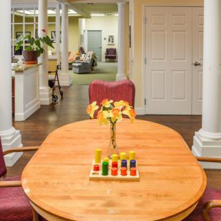 A cozy interior space featuring a wooden table with flowers and chairs, leading to an open hallway.
