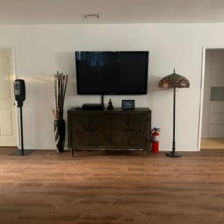 A minimalist living room setup featuring a wall-mounted television above a cabinet, with a unique lamp and decorative elements on either side.