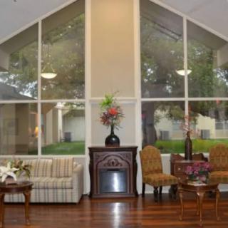 A cozy living room with large windows, featuring a sofa, chairs, a fireplace, and decorative elements.