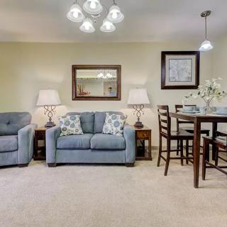 A cozy living room with a sofa and armchair, complemented by a dining area and stylish lighting.