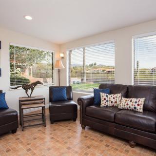 A cozy living room with dark furniture, ample natural light, and decorative accents.