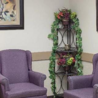 A cozy waiting area with purple chairs and decorative plants.