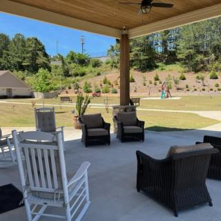 A cozy outdoor patio with comfortable seating and a view of landscaped greenery.