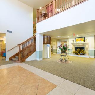 A spacious lobby area featuring a staircase, fireplace, and elegant decor.