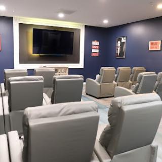 A cozy home theater room featuring comfortable seating and a large TV screen.