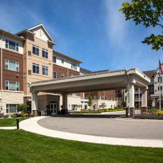 A modern residential building with a covered entrance and well-maintained landscaping.