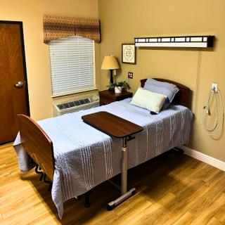 A tidy and well-organized hospital room featuring a hospital bed, a nightstand, and natural light from the window.