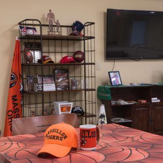 A room decorated with sports memorabilia, featuring hats, a mug, and a television.