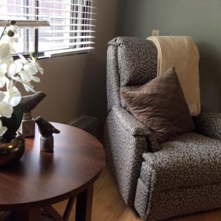 A cozy corner in a living room featuring a comfortable recliner, decorative pillows, and a small table with flowers.