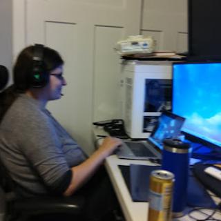 A person working at a desk with multiple screens and wearing headphones.