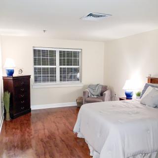 A cozy bedroom with wooden flooring, modest decor, and a comfortable bed.