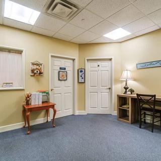 A small office waiting room with chairs, a desk, and multiple doors.
