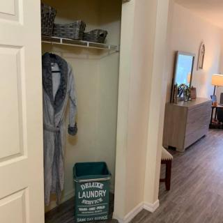 A cozy hallway with an open closet featuring a bathrobe and laundry basket.