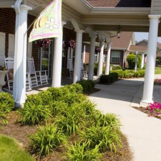 A welcoming porch with columns and neatly landscaped surroundings.