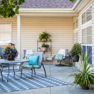 A cozy outdoor patio with a dining table, chairs, and lush plants.