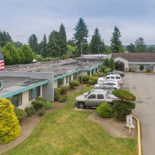 Aerial view of a motel with a parking lot surrounded by trees.