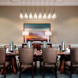A luxurious dining room with a large table, elegant chairs, and decorative chandeliers.