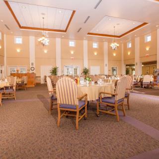 A spacious and elegantly designed dining room with high ceilings, set with tables and chairs.
