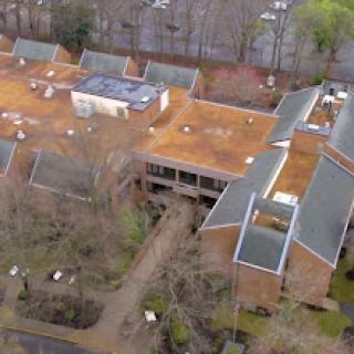 An aerial view of a complex featuring multiple buildings surrounded by trees.