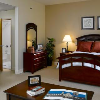 A cozy and well-decorated bedroom featuring a large bed, dresser with mirror, and warm lighting.