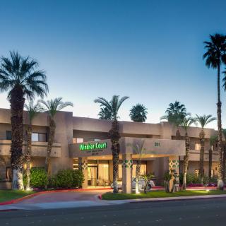 A hotel building with palm trees in the evening light.