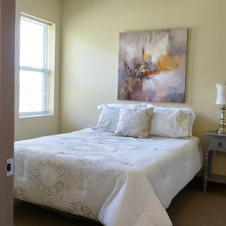 A cozy bedroom featuring a comfortable bed, stylish bedding, and decorative artwork on the wall.