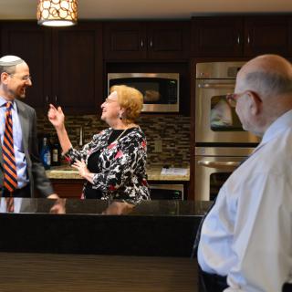 Three people engaged in a conversation in a modern kitchen setting.