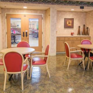 A cozy indoor dining area with red cushioned chairs and round tables.