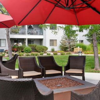 Outdoor patio area with chairs and a fire pit under a red umbrella.