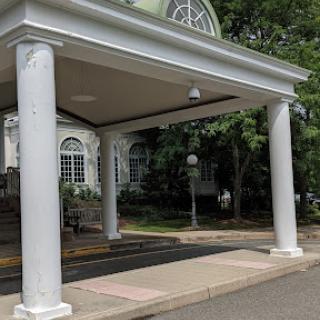 A view of a building entrance featuring elegant white columns and a canopy.