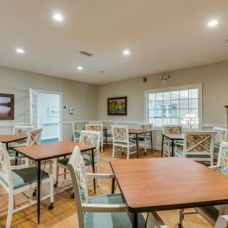 A well-lit dining area with wooden tables and chairs, featuring a warm and inviting atmosphere.