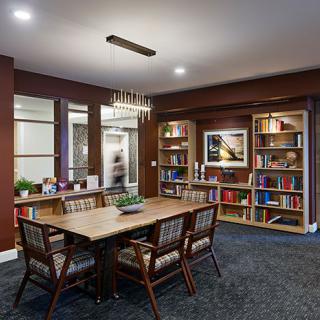 A cozy library room with a table, chairs, and bookshelves.