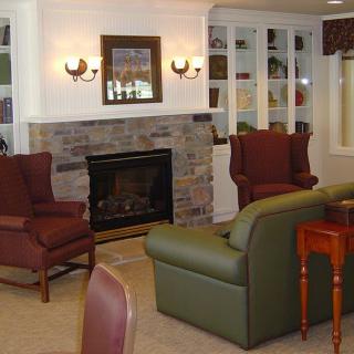 A cozy living room with a fireplace, armchairs, and bookshelves.