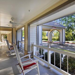 A spacious porch with rocking chairs overlooking a peaceful outdoor setting.