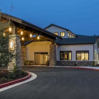 A well-lit building entrance with a curved driveway during the evening.