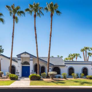 A beautiful residential building surrounded by palm trees under a clear blue sky.