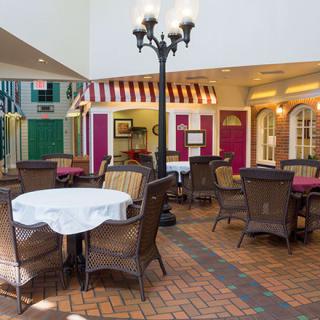 A cozy indoor cafe setting with tables and chairs arranged on a brick floor, illuminated by a vintage-style street lamp.