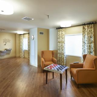 A cozy sitting area featuring two armchairs, a small table with a board game, and patterned curtains.