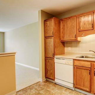 A compact kitchen with wooden cabinets, a built-in dishwasher, and a sink.