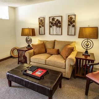 A cozy living room with a beige sofa, decorative pillows, stylish lamps, and wall art.