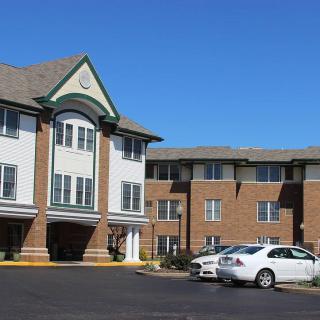 A residential building with a parking lot and cars under a clear blue sky.