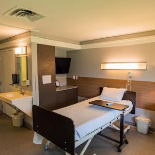 A modern hospital room with a single bed and amenities.