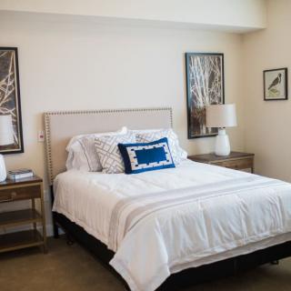 A modern bedroom with a neatly made bed, two nightstands, and stylish decor.