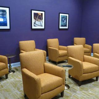 A cozy waiting area with comfortable chairs and artwork on a purple wall.
