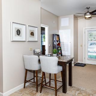 A modern dining area featuring a wooden table with bar stools, wall art, and stylish home decor in an open space.