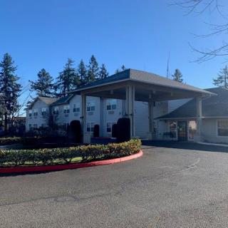 A fire station with a driveway on a sunny day, surrounded by trees.