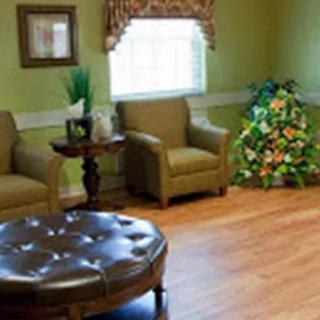 A cozy living room with comfortable chairs, a small round table, and decorative plants.