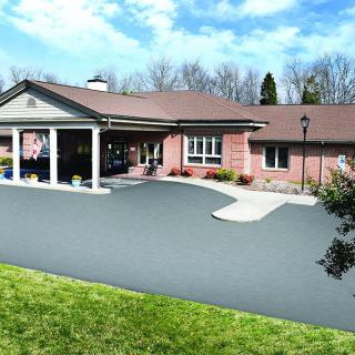 A single-story building with a covered entrance, surrounded by a driveway and landscaped front yard.