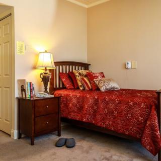 A cozy bedroom with a single bed, nightstand, and lamp.